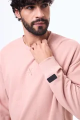 Buzo de felpa color rosado con cuello redondo, mangas largas y logo bordado en el pecho.