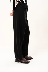 Pantalón de tiro medio con silueta curvada, más ancha en la zona de los muslos y rodillas, con cierre frontal de cremallera y botón.