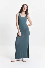 Vestido largo de punto con textura acanalada, escote redondo y tirantes anchos. Presenta una silueta ajustada al cuerpo y un tajo lateral en la parte inferior.