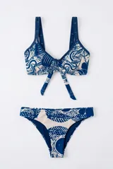 Conjunto de bikini con estampado de hojas en tonos azul marino y beige, compuesto por un top con tirantes anchos y nudo frontal, y una bombacha clásica.