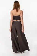 Pantalón de lino verde militar, de tiro alto y corte amplio con botamanga ancha. Cuenta con bolsillos delanteros aplicados y cierre frontal con botón y bragueta.