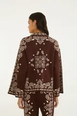 Sweater de punto color marrón con diseño estampado estilo paisley en tono crudo, cuello camisero con escote en V y cordones decorativos, mangas largas y calce amplio.