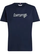 Remera de manga corta, cuello redondo, color azul marino. Presenta el logo 'tommy' estampado en la parte frontal con pedrería blanca (strass) que simula flores.