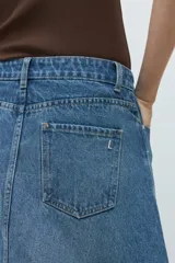 Falda midi de jean en color azul medio, con diseño de paneles verticales y corte acampanado. Presenta cierre frontal con botón y bolsillos laterales.