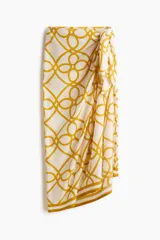 Pareo en tejido liviano suave con diseño estampado de cuerdas en color mostaza sobre fondo blanco, ideal para llevar a la playa, con diseño para atar adelante.