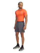 Short deportivo Under Armour Vanish Woven, color gris con detalles en naranja. Presenta cintura elástica con logo de la marca, bolsillos laterales y tejido ultraligero de secado rápido con paneles de ventilación.
