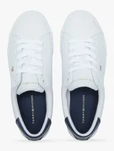Zapatillas urbanas Tommy Hilfiger de corte bajo, color blanco con detalle azul en el talón. Tienen diseño con cordones, suela de goma blanca y pequeño logo bordado en el lateral.