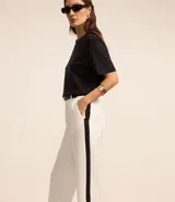 Pantalón de vestir blanco de crepé, corte recto, con trabillas en la cintura, bolsillos laterales y raya lateral negra.