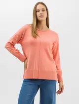 Buzo de tejido fino color salmón, con manga larga, puños y ruedo ancho en punto rib. Presenta un pespunte central decorativo en la parte delantera y tajos en los laterales.