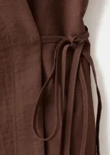 Camisa cruzada de color marrón, con diseño recto, cuello camisero, manga larga y cierre de lazo en la cintura con botones.