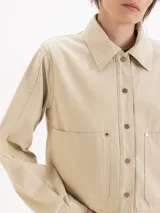 Chaqueta de gabardina color rosado con efecto desgastado, de calce relajado, cuello clásico marrón, bolsillos delanteros aplicados y cierre frontal con broches metálicos a presión.