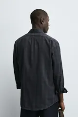 Camisa de corte regular fit confeccionada en tejido de algodón con estampado de cuadros oscuros. Presenta cuello abotonado, manga larga con puños abotonados y cierre frontal con botones.