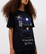 Remera negra de algodón con cuello redondo, mangas cortas y estampa frontal de la saga Harry Potter con ilustración nocturna del castillo de Hogwarts y el texto First Years This Way.