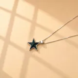 Collar de cadena fina de plata 925 con dije en forma de estrella, con centro de resina color azul oscuro y borde plateado.