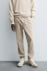 Pantalón tipo jogger de corte slim fit, confeccionado en tejido de algodón con elasticidad. Presenta cintura elástica ajustable con cordón, bolsillos frontales, bolsillos traseros de vivo y bajos con puños elásticos.