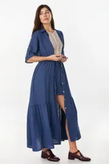 Vestido camisero largo de lino italiano color celeste, de corte relajado, con mangas caídas, jareta ajustable en la cintura, cierre frontal de botones y bajo con volado fruncido.