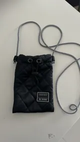 Porta celular negro acolchado con cordón largo a rayas blancas y negras.