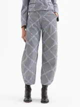 Pantalón de corte mom fit confeccionado en tejido con diseño de microcuadros y bordado de labios en color celeste que forman un patrón de rombos. Presenta una cintura con efecto de cinto integrado, bolsillos laterales con detalles en cuero color borravino y pinzas en las rodillas que aportan volumen. El cierre es mediante gancho, botón interno y cremallera.