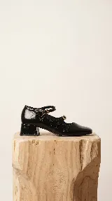 Zapatos tipo Mary Jane de cuero negro con acabado texturizado, doble tira con hebillas metálicas doradas y taco cuadrado bajo.