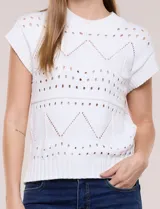 Buzo de tejido de algodón color blanco, de silueta semi holgada, con motivos de calados geométricos y guardas en zigzag. Cuenta con escote redondo, mangas cortas estilo japonesa y terminaciones acanaladas.