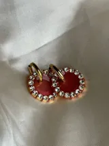 Aros colgantes dorados con dije circular de resina color turquesa, bordeado con strass. El arito es de acero quirúrgico.