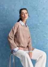 Sweater blanco de punto con diseño holgado, cuello redondo, mangas largas acampanadas y detalles de textura horizontal en el tejido.