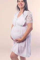 Camisón maternal de algodón elastizado color blanco, con escote redondo, mangas cortas de puntilla y detalle de puntilla en los hombros. Presenta botones en toda la parte delantera y elástico bajo el busto para mayor sujeción.