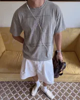 Remera de corte oversize color gris con efecto stone wash. Presenta un estampado gráfico central enmarcado en un recuadro negro, que muestra una silueta humana rodeada por líneas curvas de color violeta y el texto 'FIG. 1 LOS DE AFUERA SON DE PALO'.