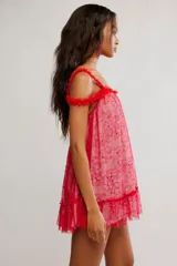 Vestido corto de tul bordado color rojo y rosado, con escote recto, volados sobre los hombros, tiras finas regulables y ruedo terminado en volado. Caída suelta y liviana.