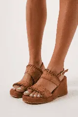 Sandalia de taco chino y plataforma forrada, color tostado, con doble tira ancha en el empeine con detalles de costuras y pespuntes artesanales. Cuenta con tira ajustable con hebilla en el talón.