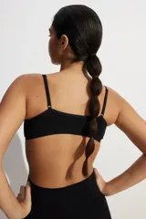 Sujetador suave de punto color negro, con tirantes ajustables y copas forradas con relleno extraíble. Presenta un ribete de canalé en el bajo y no tiene cierre.