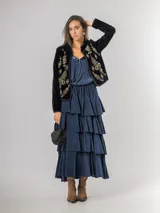 Falda midi de micro corderoy azul marino, con diseño de volados escalonados y cintura elástica. Presenta un corte asimétrico, siendo ligeramente más corta en la parte frontal.