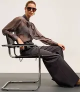 Pantalón de sastrería de corte recto y tiro alto, con diseño de pierna ancha, trabillas en la cintura, cierre frontal con botón y cremallera, y bolsillos laterales con costuras verticales.