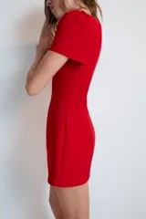 Vestido mono corto de color rojo, con cuello redondo y mangas cortas abullonadas. Cuenta con forro interior tipo shorts combinado a tono y cierre en la espalda con cremallera oculta.