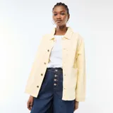 Chaqueta vaquera color amarillo claro, de corte recto y largo medio, con cuello camisero, cierre frontal de botones y dos bolsillos delanteros de parche.