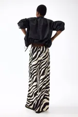 Pantalón largo de corte holgado y piernas amplias con estampado animal print de cebra. Cuenta con tiro alto, cintura elástica y cordón ajustable.