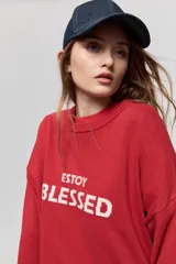 Sweater de punto marrón de tejido liviano y calce relajado, con hombros caídos, cuello redondo y puños y cintura en rib. Cuenta con una estampa tejida en el frente con la frase "Estoy Blessed" en color amarillo.
