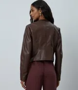 Campera básica de cuero sintético (PU) color marrón oscuro, con cuello redondo, cierre frontal y recortes decorativos. Cuenta con mangas largas y bolsillos con cierre.