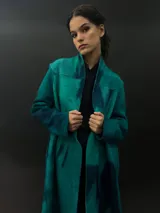 Tapado largo gris de lana merino con bolsillos laterales y corte particular en los hombros.