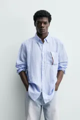 Camisa regular fit de manga larga con diseño a rayas verticales celestes y blancas. Cuenta con cuello abotonado, bolsillo de parche en el pecho y cierre frontal con botones.