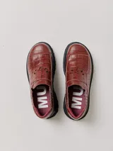 Mocasines de plataforma alta con diseño de estilo rebelde. Presentan un estampado de cuadros en tonos violeta y amarillo, confeccionados en lona con detalles en cuero. Cuentan con una suela robusta y elásticos laterales ocultos para facilitar el calce.