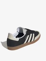 Zapatillas Adidas Samba OG, color negro con las tres tiras laterales en blanco y suela de goma marrón.