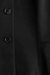 Chaleco de sarga con escote de pico, cierre frontal de botones y diseño con peplum acampanado en la cintura.