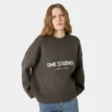 Sweater de punto grueso color marrón oscuro, con corte cuadrado y ligeramente corto. Presenta cuello redondo, puños y ruedo acanalados, y el logo de la marca Eme Studios junto a la frase 'curated by ben ice' en jacquard color crema en el frente.
