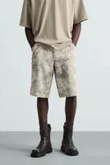 Bermuda relaxed fit de algodón, color beige con estampado abstracto en tonos grises. Cuenta con cinco bolsillos y cierre frontal de cremallera y botón.