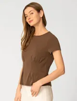 Remera blanca de manga corta con cuello redondo, confeccionada en una mezcla de modal, poliéster y elastano. Presenta un diseño con alforzas verticales en el frente que aportan estructura y una silueta relajada.