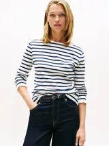 Remera de manga larga con cuello barco y diseño de rayas horizontales en azul marino y blanco. Presenta un pequeño logo bordado en el pecho y puños con detalle de volado.