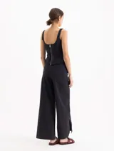 Pantalón wide leg negro de tiro medio-alto con elástico en la espalda, cinto con hebilla y tajos en las botamangas.