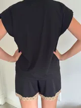 Pijama celeste de algodón con textura acanalada, compuesto por una remera de mangas cortas con escote en V y puntilla blanca, y un short con elástico en la cintura, lazo y terminación con puntilla.