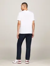 Remera de algodón Tommy Hilfiger, color blanco, con cuello redondo y manga corta. Presenta el logo de la marca bordado en el pecho en tipografía cursiva y la bandera distintiva bordada en la manga.